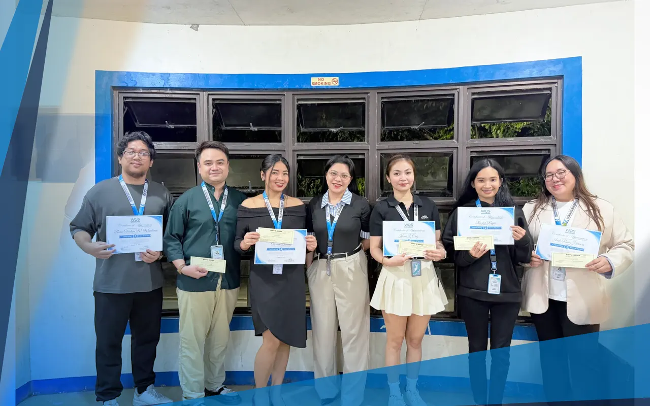 Seven team members holding tenure certificates in front of the office windows